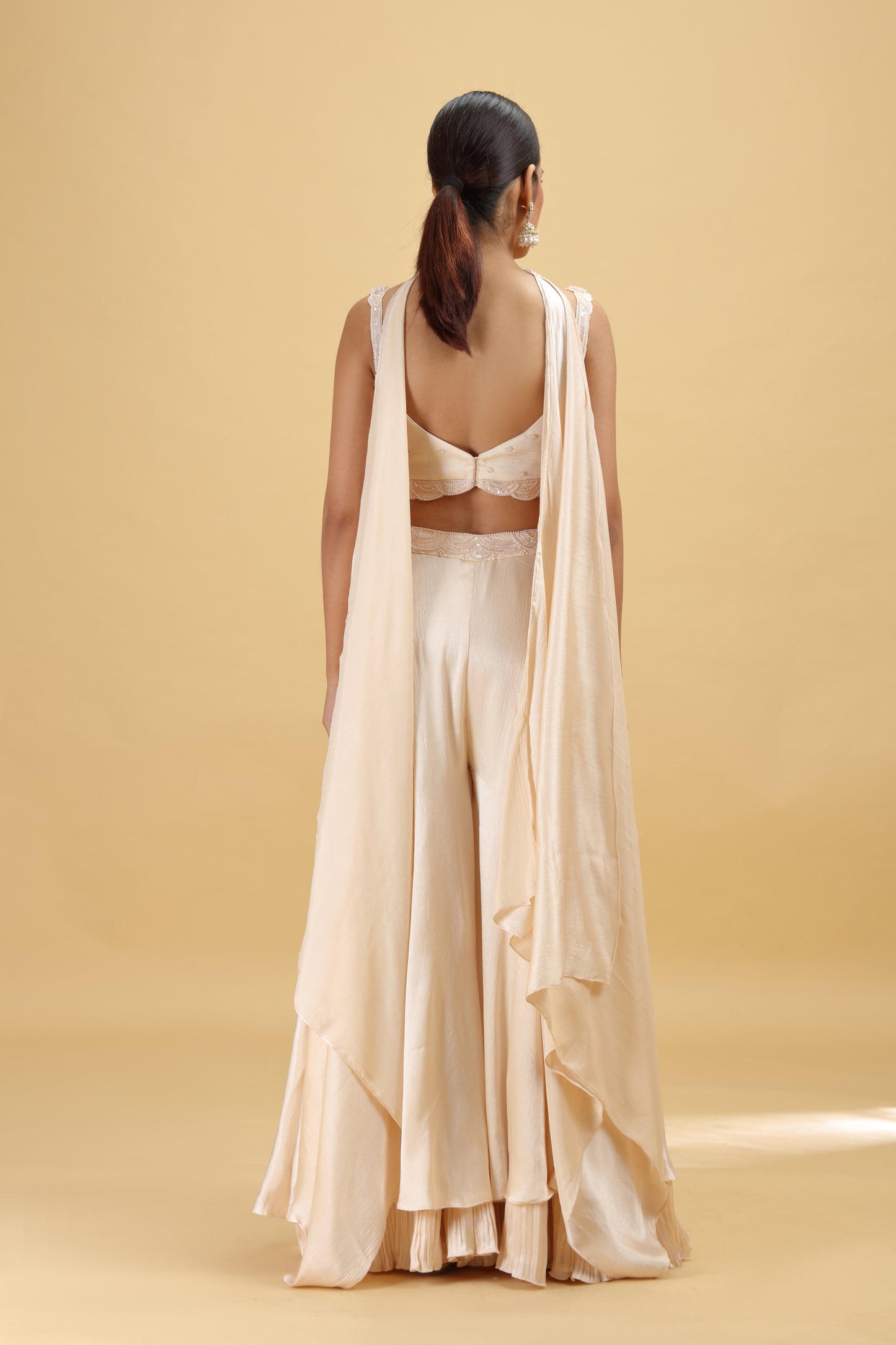 Woman wearing a beige outfit with a drape on a beige background