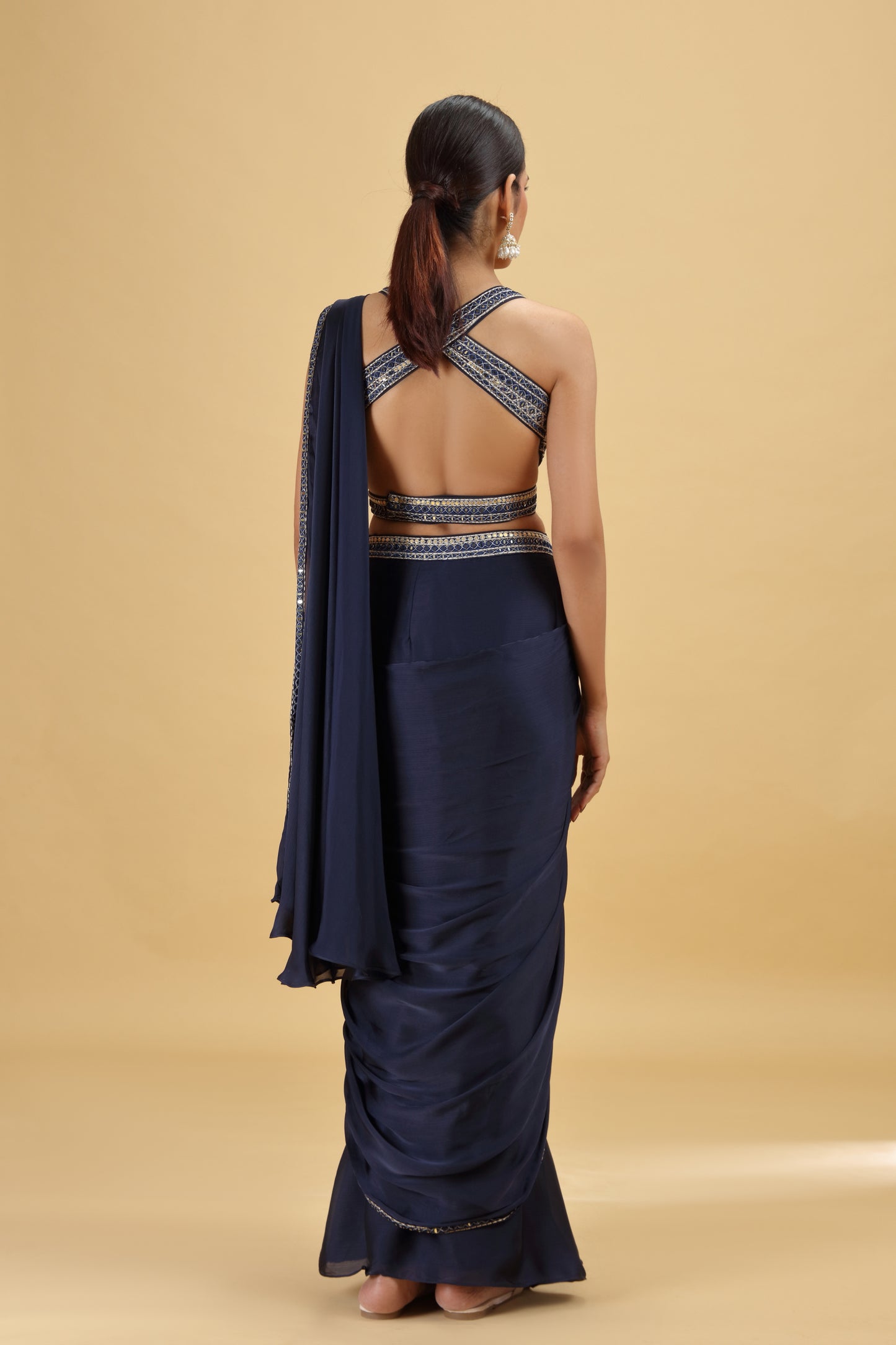Woman wearing a navy blue saree with a beige background