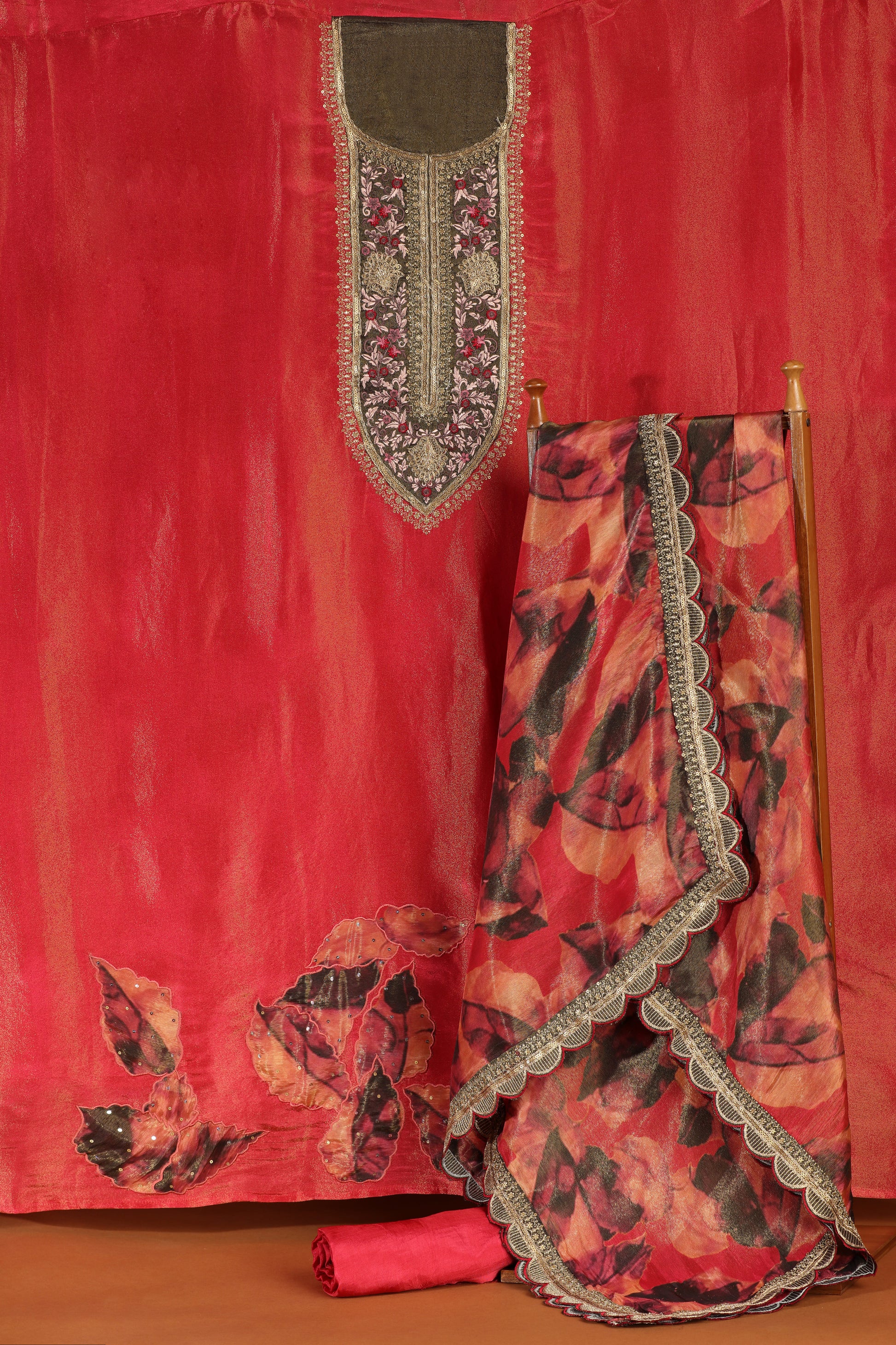Red fabric with embroidered details on a wooden stand against a red background