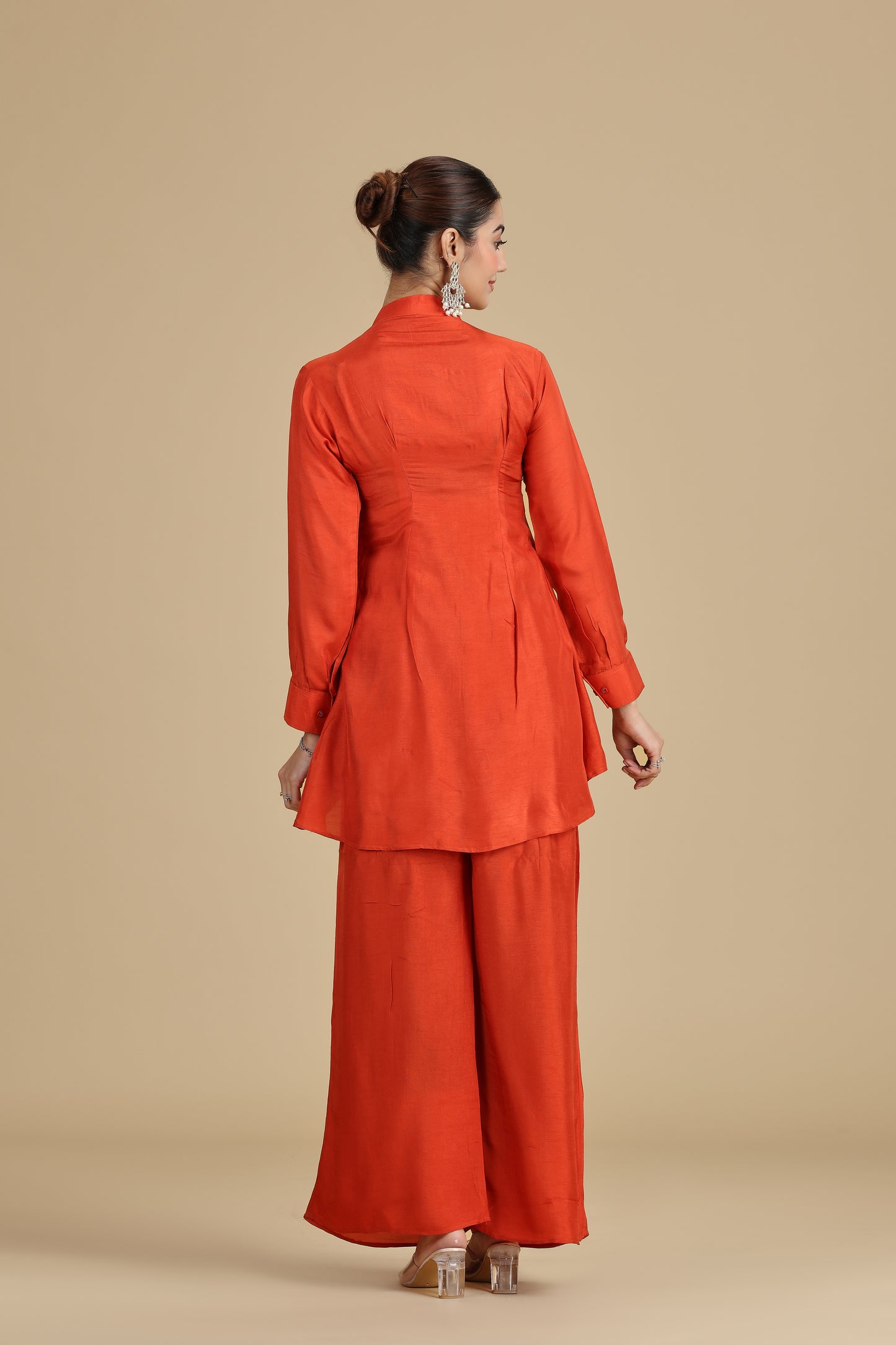 Woman backview wearing an orange outfit on a beige background