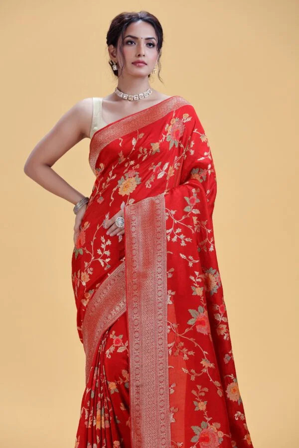 Woman posing in a vibrant red silk saree adorned with subtle gold floral embroidery, draped with pleats and pallu showcased.