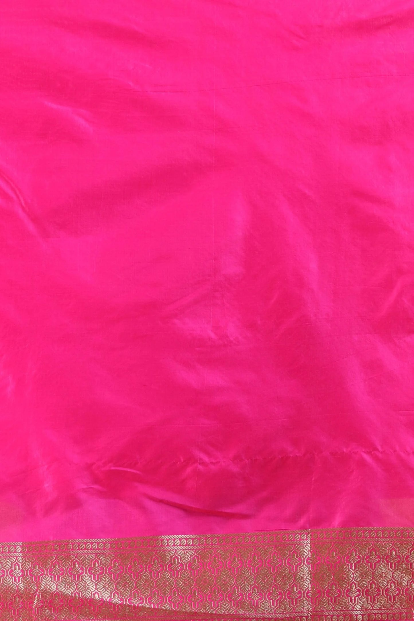 Bright pink fabric with a shiny texture, featuring an ornate gold border at the bottom