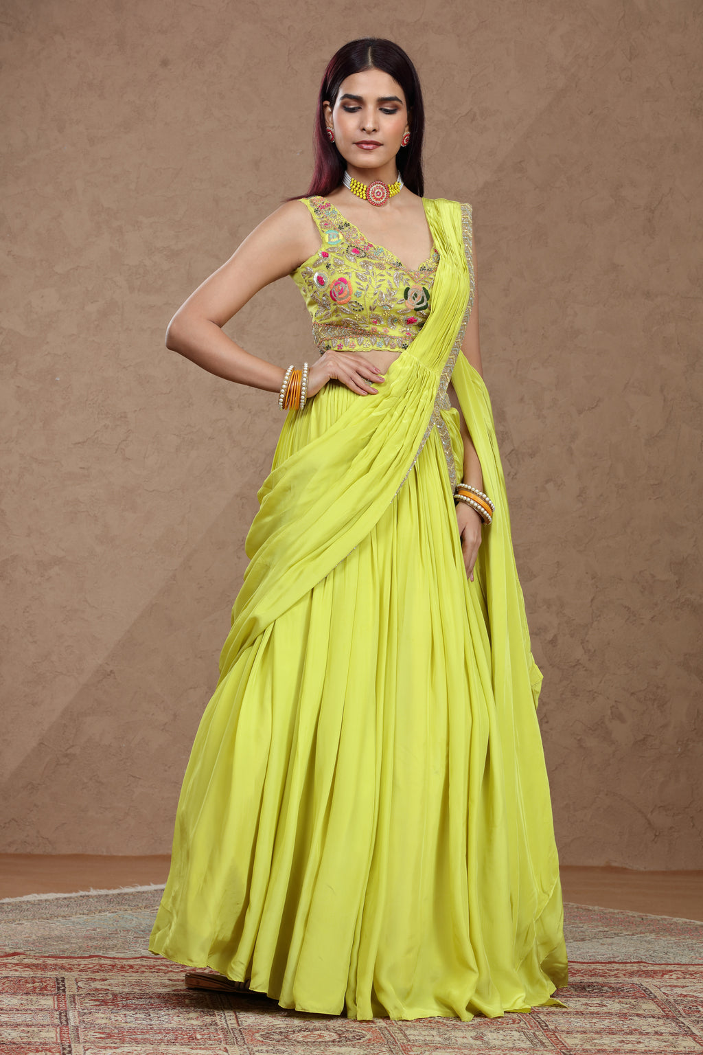 Woman wearing a bright yellow saree with a matching blouse against a brown background