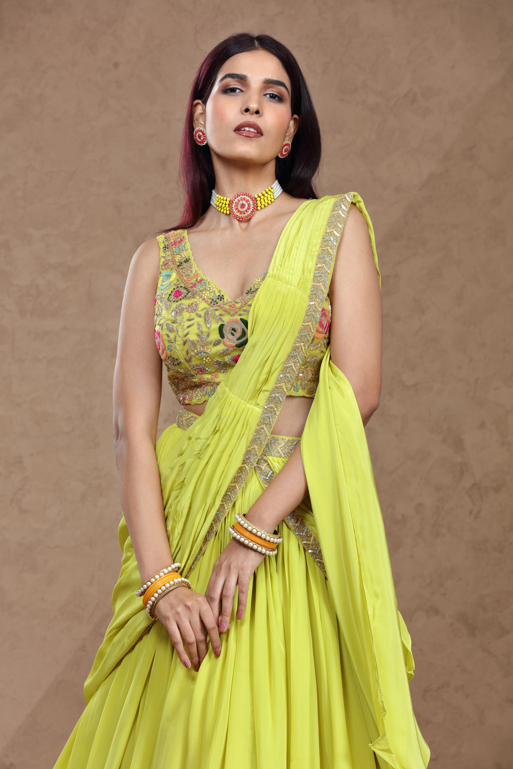 Woman wearing a bright yellow saree with a matching blouse against a brown background