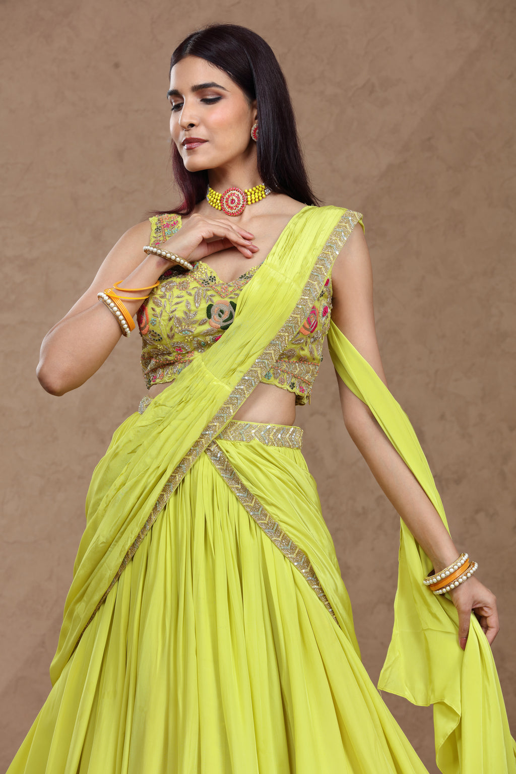 Woman wearing a bright yellow saree with gold accents against a brown background