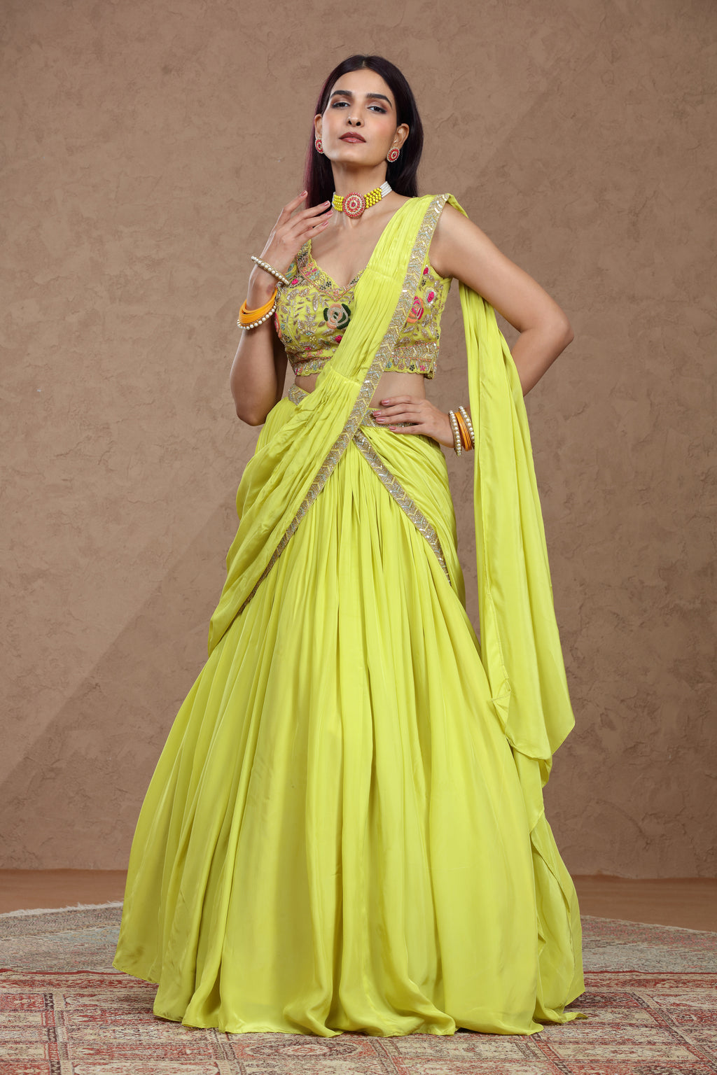 Woman wearing a bright yellow saree with a matching blouse against a brown background
