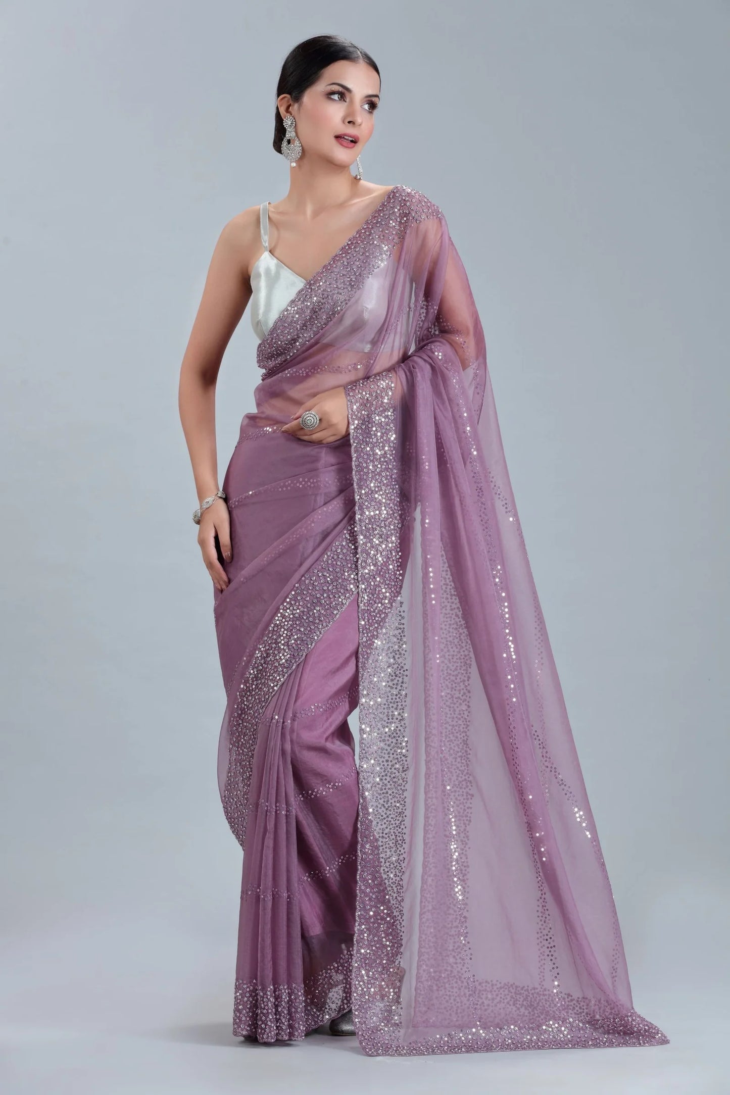 Woman wearing a mauve saree with silver border on a gray background