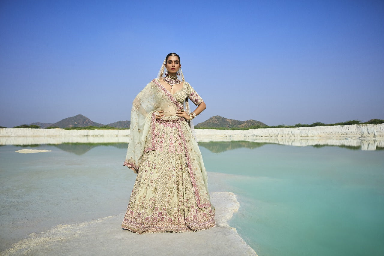 Woman in Sage Green Raw Pure Silk Lehenga Set standing on a platform with a scenic background