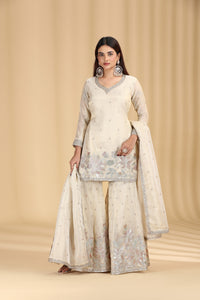Woman wearing a cream traditional outfit with floral patterns on a beige background
