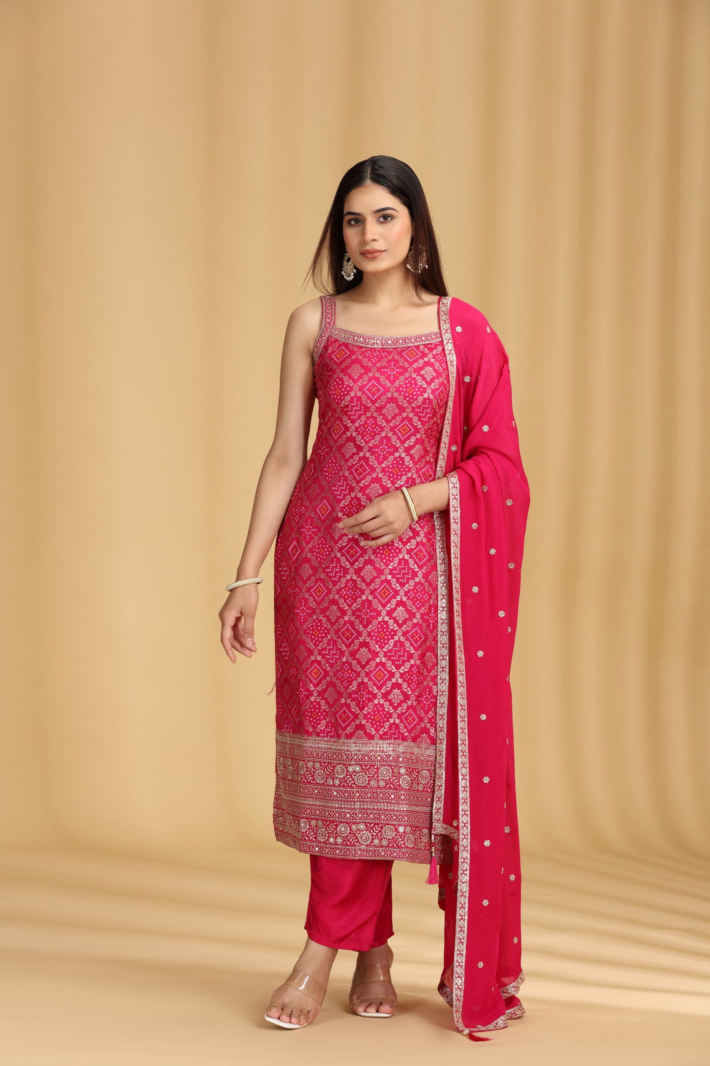 Woman wearing a pink traditional outfit with a matching dupatta on a beige background