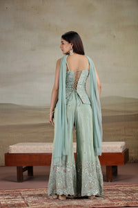 Woman in a light green traditional outfit with a matching dupatta, standing against a neutral background.