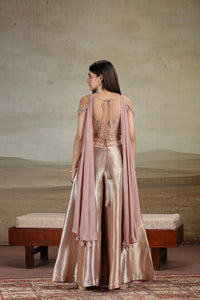 Woman in a elegant outfit with a beige and pink color scheme, standing against a neutral background.