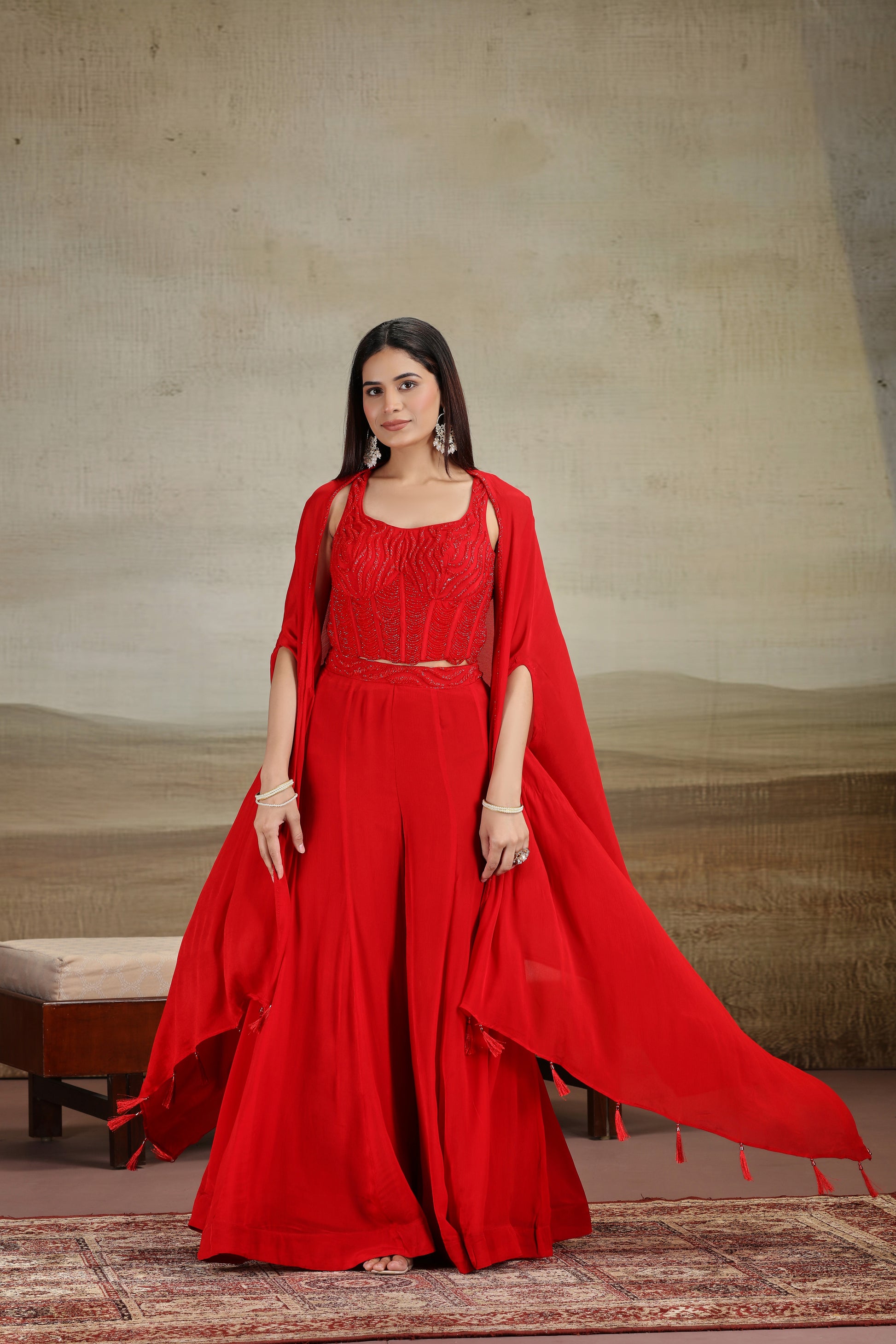 Woman wearing a red outfit with a cape against a neutral background