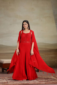 Woman wearing a red outfit with a cape against a neutral background