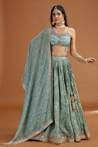 Woman wearing a traditional green outfit with a matching dupatta on a brown background