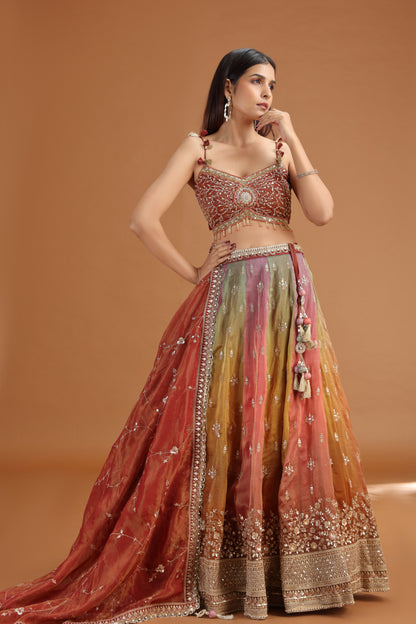 Woman wearing a maroon tissue lehenga set with mirror & zardosi work