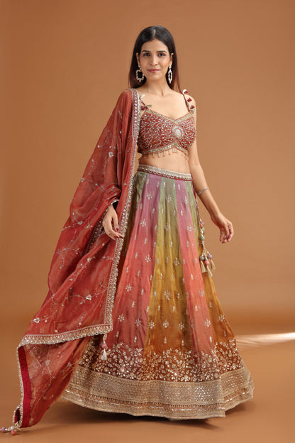 Woman wearing a traditional maroon tissue lehenga with mirror & zardosi work