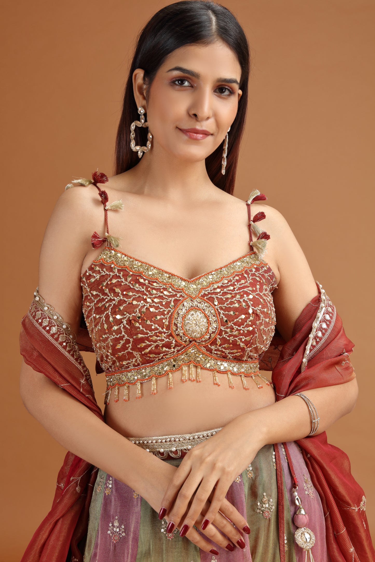 Woman wearing a maroon tissue lehenga set with mirror work 