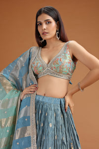 Woman wearing a traditional wear with a blue and green dupatta against a brown background
