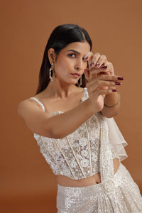 Woman in a white saree against a brown background