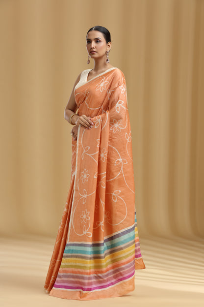 Woman wearing an peach saree with white floral patterns on a beige background
