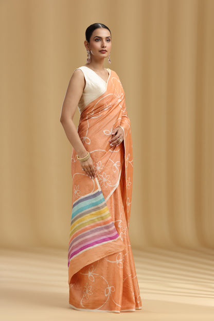 Woman wearing an peach saree with a rainbow design on a beige background