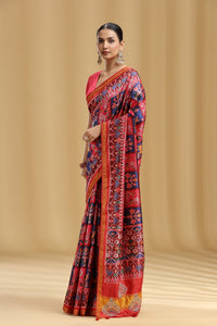 Woman wearing a vibrant saree with a geometric pattern on a beige background