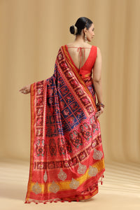 Woman wearing a red saree with intricate patterns on a beige background