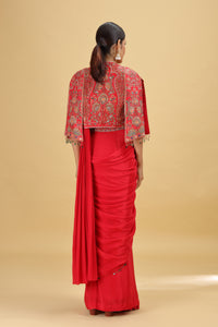 Woman wearing a red saree with gold embroidery on a beige background