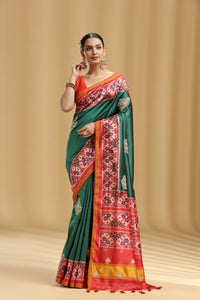 Woman wearing a green and red saree with a beige background