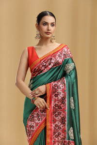 Woman wearing a traditional saree with a red and green design on a beige background