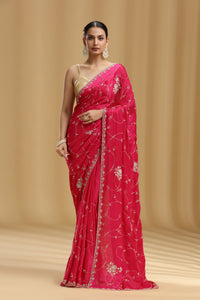 Woman wearing a pink saree with floral patterns on a beige background