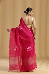 Woman wearing a pink saree with white patterns on a beige background