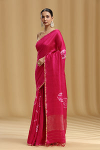 Woman wearing a pink saree with white embroidery on a beige background