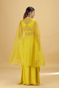 Woman wearing a yellow outfit with a sheer overlay against a beige background