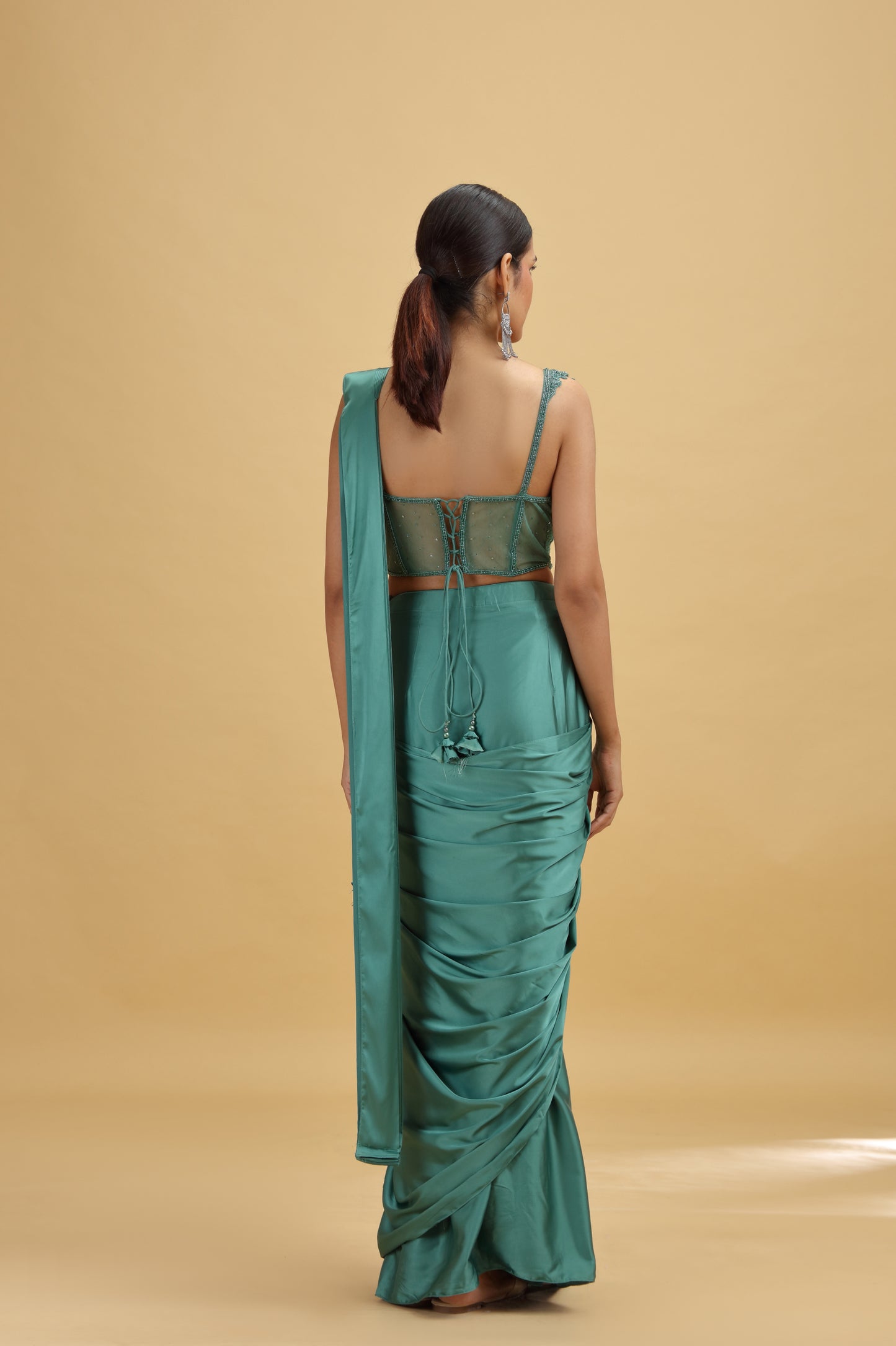 Woman showing back wearing a green saree 