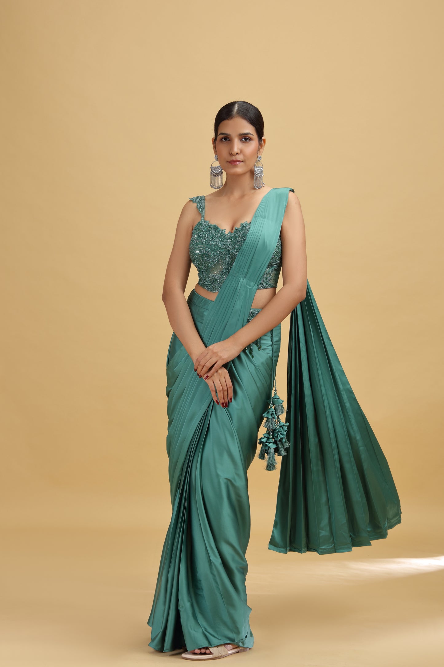 Woman wearing a teal green crepe saree with net stitched blouse