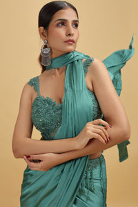Woman wearing a green crepe saree with stitched net blouse & moti-sequins work