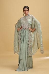 Woman wearing a pista green salwar suit with floral embroidery on a beige background