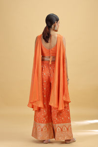 Woman wearing an orange traditional outfit with a beige background