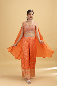Woman wearing an orange traditional salwar kameez suit with a cape on a beige background