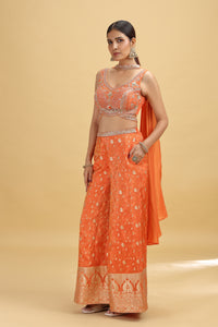 Woman wearing an orange tissue salwar suit with sequins, cutdana & zardosi work
