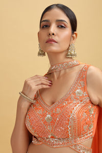 Woman wearing an orange embroidered blouse with intricate designs on a beige background