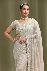 Woman wearing a silver saree with a plain background