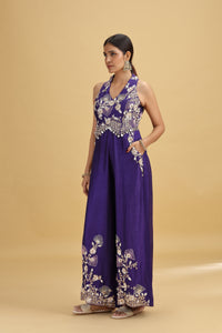 Woman wearing a purple dress with floral embroidery on a beige background