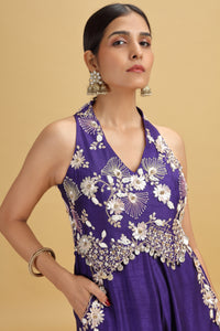 Woman wearing a purple floral salwar kameez bead details on a beige background