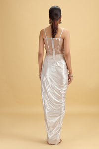 Woman wearing a silver metallic gown against a beige background