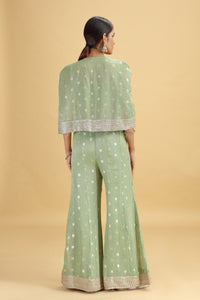Woman wearing a green traditional outfit with a beige background
