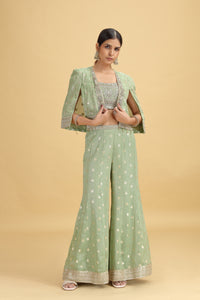 Woman wearing a green silk salwar suit with a beige background