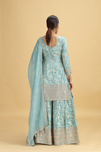Woman wearing a light blue traditional outfit with a beige background